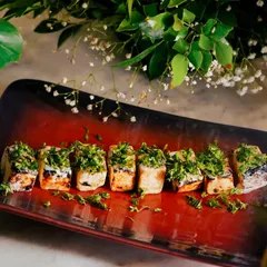 Another look at the Paneer Ajamod Tikka, plated on a rustic red dish that makes the green herbs pop.