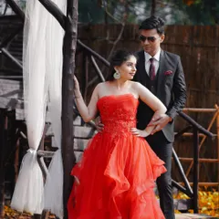 A dramatic and romantic pose from a pre-wedding shoot. The bride's flowing red gown and the couple's intense gaze make for a truly cinematic shot.