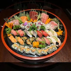 An overhead view of one of our large, custom-made sushi and sashimi platters. This one features a vibrant mix of nigiri, maki rolls, and fresh sashimi, garnished with edible flowers for a beautiful presentation.