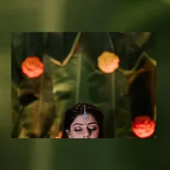 A creative and serene shot focusing on the mother-to-be during her ceremony. The details of her bindi and the traditional decor in the background add cultural context.