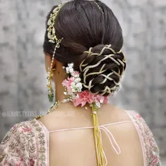 For this bridal bun, I wove intricate patterns using golden thread to create a unique basket-weave effect. The look was finished with fresh pink carnations and baby's breath, adding a touch of softness to the structured updo.