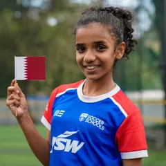 A young girl proudly holds the flag of Qatar, excited about our international expansion. We are thrilled to bring our coaching philosophy to girls around the world.
