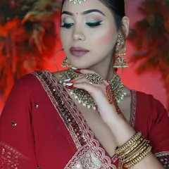 The quintessential Indian bride in classic red. This look combines a modern green winged liner with traditional red attire and gold jewelry for a timeless appeal.