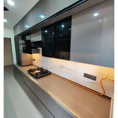 A sleek parallel kitchen with glossy grey cabinets and a white marble backsplash. The under-cabinet lighting illuminates the countertop, making it a bright and functional workspace.