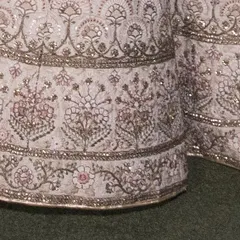 The border of the bridal lehenga skirt, featuring multiple layers of detailed floral and traditional motifs. This heavy work gives the outfit its grand appearance.