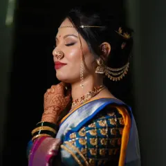 A side profile showcasing the complete Maharashtrian bridal look. You can see the detailed eye makeup, the elegant hairstyle with traditional accessories, and the iconic 'nath' that completes the look.