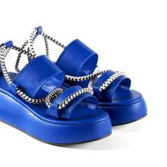 A close-up detail shot of Jeetinder Sandhu's vibrant blue platform sandals. This e-commerce style photo on a clean white background highlights the unique design, rope-like straps, and quality construction of the footwear.
