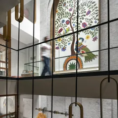 The focal point of the Slender House is this triple-height custom artwork, 'The Tree of Life'. It illustrates the family's journey with personal symbols, making it a deeply emotional and connective element visible from every room.