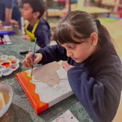 Another student carefully outlines her Mexican church design before starting to paint. This project teaches sketching, composition, and color blocking.