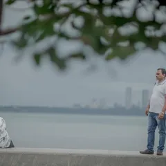A candid shot capturing a quiet moment at Marine Drive, with the iconic Mumbai skyline in the background. This tells a story of love in the city.