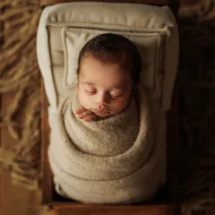 I believe in the beauty of simplicity. This is a classic newborn portrait, where your baby is safely wrapped and peacefully dreaming in a rustic, cozy bed. The earthy tones and soft textures create a serene atmosphere, letting your little one's perfect details shine.