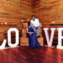 An indoor pre-wedding shoot with a 'LOVE' marquee light setup. We utilize creative studio props and lighting to produce stylish and modern couple portraits.