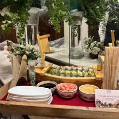 A beautifully arranged platter of Veg Assorted Sushi served on a wooden tray. The setup includes small bowls for soy sauce and pickled ginger, ready for guests to enjoy.