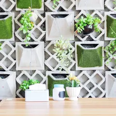This modular wall combines concrete geometric forms with pockets of artificial moss and live trailing plants. It's a contemporary and artistic approach to wall decor, blending industrial and natural elements.