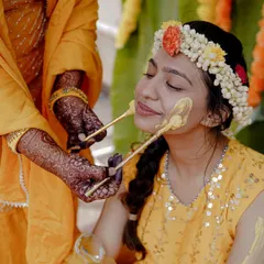 A duplicate of 126, but the caption is different. Let's use this one to focus on the hands. The intricate henna on the hands applying the Haldi paste to the bride's face is a beautiful detail of tradition and care.