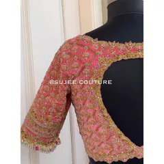 A detailed view of a pink velvet blouse with a heart-shaped back cutout. The entire surface is covered in a jaal pattern of zardozi and beadwork, making it a true statement piece.