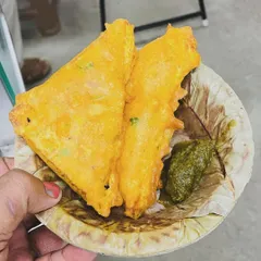 A classic rainy-day snack: bread pakoda. Here you can see two crispy, golden-fried bread pakodas served on a leaf plate with our homemade green chutney.