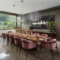 A dining room should be a place for memorable gatherings. For this space, I chose dusty pink chairs to add a touch of warmth and personality against the stone-clad walls. The solid wood table with its dancing brass base and the ethereal Meshmatics Chandeliers create an ambience that is both elegant and inviting.