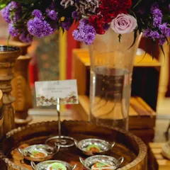 Mutton Galouti Kebabs served in small, individual silver bowls, garnished and ready to be served. The setup is enhanced with a beautiful floral arrangement in the background.