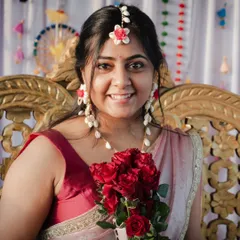 A bride's happiness is radiant. This close-up portrait during her Haldi ceremony captures her beautiful smile and the excitement of the moment, framed by a bouquet of fresh red roses.