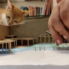 A photo of a cat curiously looking over the architectural model of our space, a fun behind-the-scenes moment from our design process.