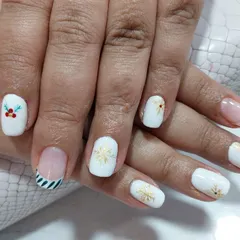 Get into the holiday spirit with this classy Christmas manicure. It features a crisp white base with hand-painted holly, gold snowflakes, and festive striped accent nails.