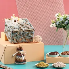 A pastel blue woven jute box, elegantly decorated with a lace bow and flower. This hamper is shown with various gourmet snacks, highlighting its versatility.