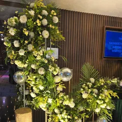 A crescent-shaped floral arrangement for a Sangeet ceremony entrance. This piece uses white chrysanthemums and greenery, accented with small disco balls for a touch of modern fun.