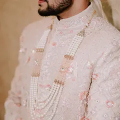 A detail shot of the groom's sherwani and the elegant pearl necklace (satlada), highlighting the richness of his wedding attire.