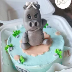 Hip Hippo Hurray for a birthday. This cake features a cute, three-dimensional hippo made entirely of fondant, sitting in a little pond of blue buttercream.