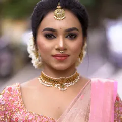 A soft and elegant bridal portrait. The makeup features a subtle smokey eye and a natural base, paired with a pink saree for a fresh and modern take on the traditional look.