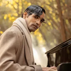A profile shot for John Jacobs, capturing the model at the piano in a classic winter coat, creating a narrative for the eyewear campaign.