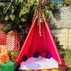 A cozy teepee tent setup for an outdoor Haldi function. This makes for a unique and intimate photo corner for the bride and her friends.