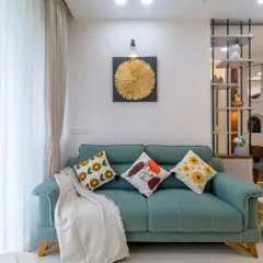 A comfortable and stylish living room with a teal sofa and vibrant cushions. The gold wall art and modern partition add touches of elegance and personality to the space.