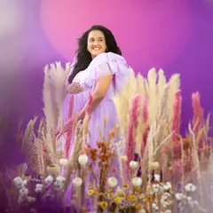 A joyful and vibrant portrait in a field of lavender-hued flowers. The mom-to-be's happy expression and the colorful setting create a feeling of pure bliss.