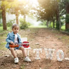 A cool and casual outdoor birthday shoot for a two-year-old. The natural path and trees create a beautiful, rustic backdrop.