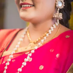 A detailed close-up of a bride's traditional Maharashtrian jewelry. The focus is on her unique seed-based necklace and earrings, showcasing the intricate and meaningful accessories of a cultural wedding.