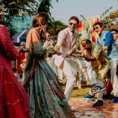 A fun-filled moment from the wedding festivities, showing the couple and their guests engaged in a playful game of tug-of-war.