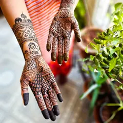 This engagement henna tells a story with traditional symbols. One hand features a prominent Ganesha motif for good luck, while the other includes peacock and elephant elements, all woven into a dense, celebratory design.