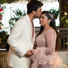 A tender forehead kiss under a neon sign that says "It Was Always You". A perfect, romantic shot from a chic cocktail party.