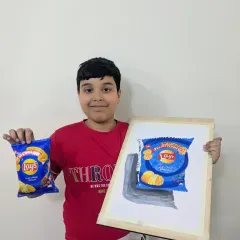 A fun and challenging object study. This student holds up his impressive painting of a Lays chip packet next to the real thing, showcasing his skill in capturing details and branding.