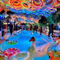 We transformed this space into a vibrant St. Tropez beach club, complete with a pool filled with colorful floats, swan inflatables, and a ceiling of rainbow-hued rings. This design captures the fun and luxury of a glamorous poolside soiree.
