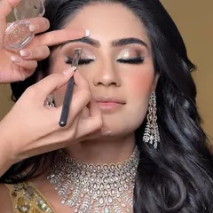 A close-up of the eye makeup process. I'm carefully blending a soft, shimmery shadow on the lid to create a glamorous yet sophisticated look, perfect for an evening event.