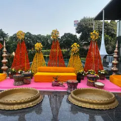 This poolside Haldi decor at Udman Greater Noida features vibrant marigold cones in orange and yellow. The setup is completed with traditional brass urlis and colourful seating, reflecting beautifully on the water.