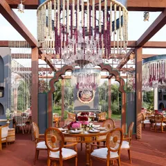 A stunning dining setup under a custom-built pergola. The massive floral chandeliers, a signature of my designs, add a sense of grandeur and romance to the guest dining experience.
