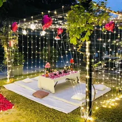 This image shows the intimate dinner arrangement inside our garden cabana proposal setup. The space is enclosed by curtains of fairy lights, creating a magical atmosphere for a private celebration.