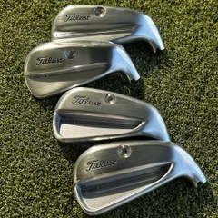 A full set of brand new Titleist irons, including the T150, T250, and T350 models, laid out on the turf. We have options for every skill level, from tour players to game improvement seekers.
