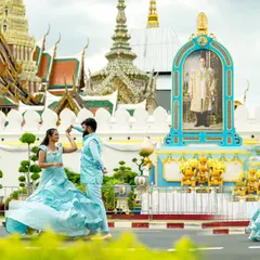 A playful, dynamic shot in front of the Grand Palace in Bangkok, with the couple in matching blue outfits that pop against the scenery.