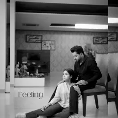 A tender black and white portrait of the couple in a modern living room, capturing a quiet, intimate moment with the word "Feeling" overlaid.