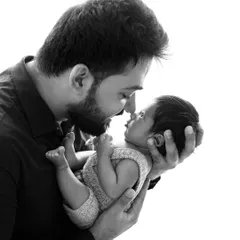 A beautiful black and white portrait of a father and his newborn. The high-contrast lighting creates a powerful and emotional image focused on their connection.